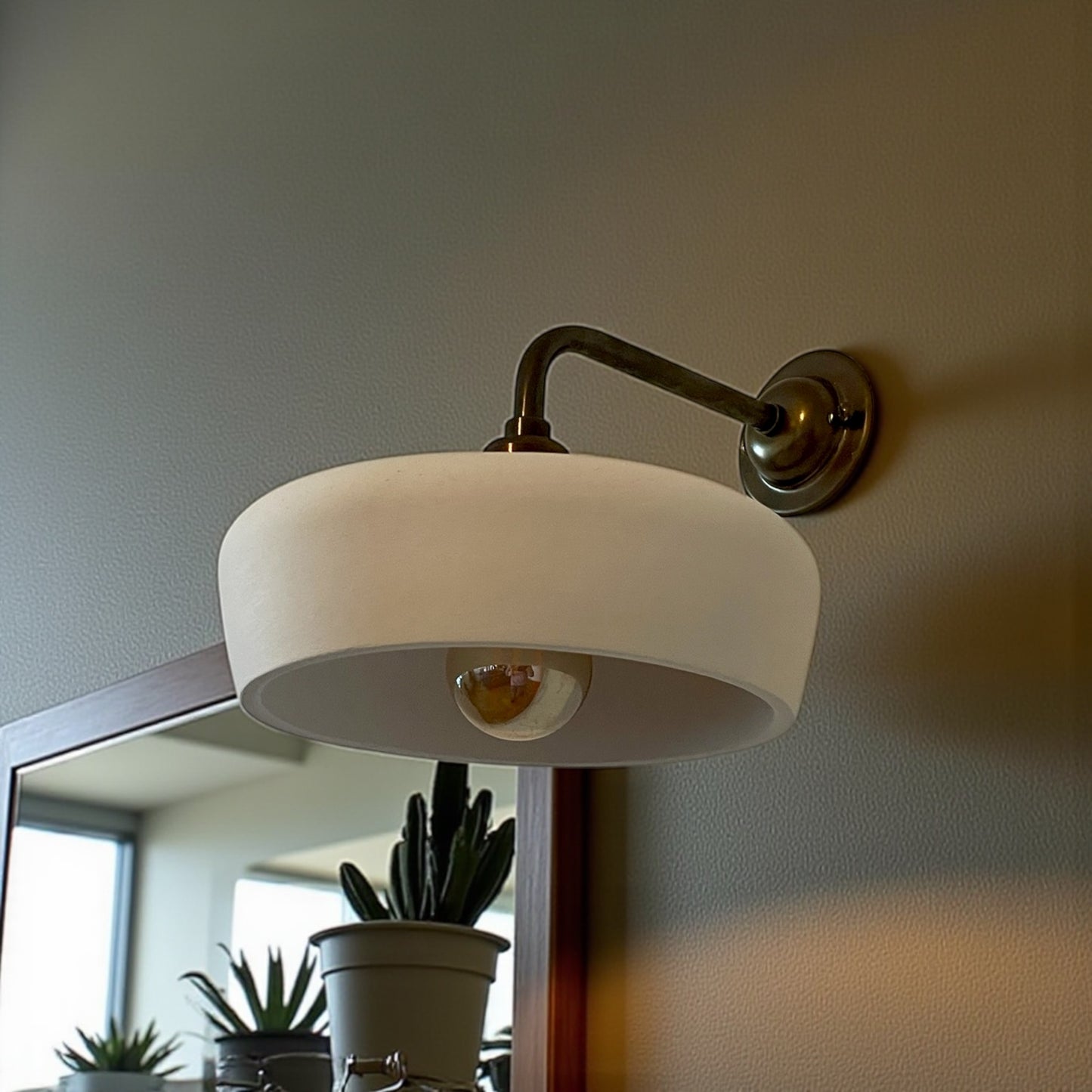 Wall-mounted lamp with a white shade on a neutral wall.