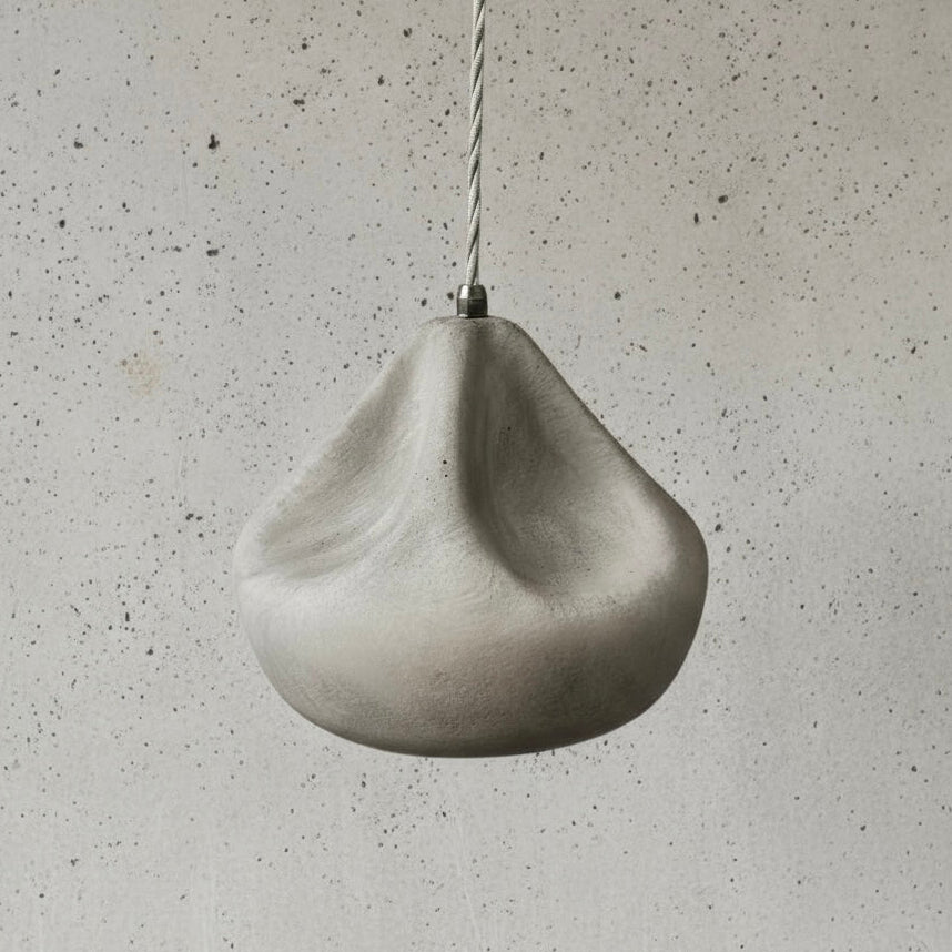 Concrete pendant light hanging against a textured gray wall