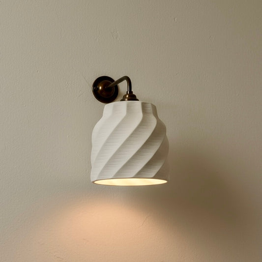 Wall-mounted light fixture with a textured white shade on a beige wall.