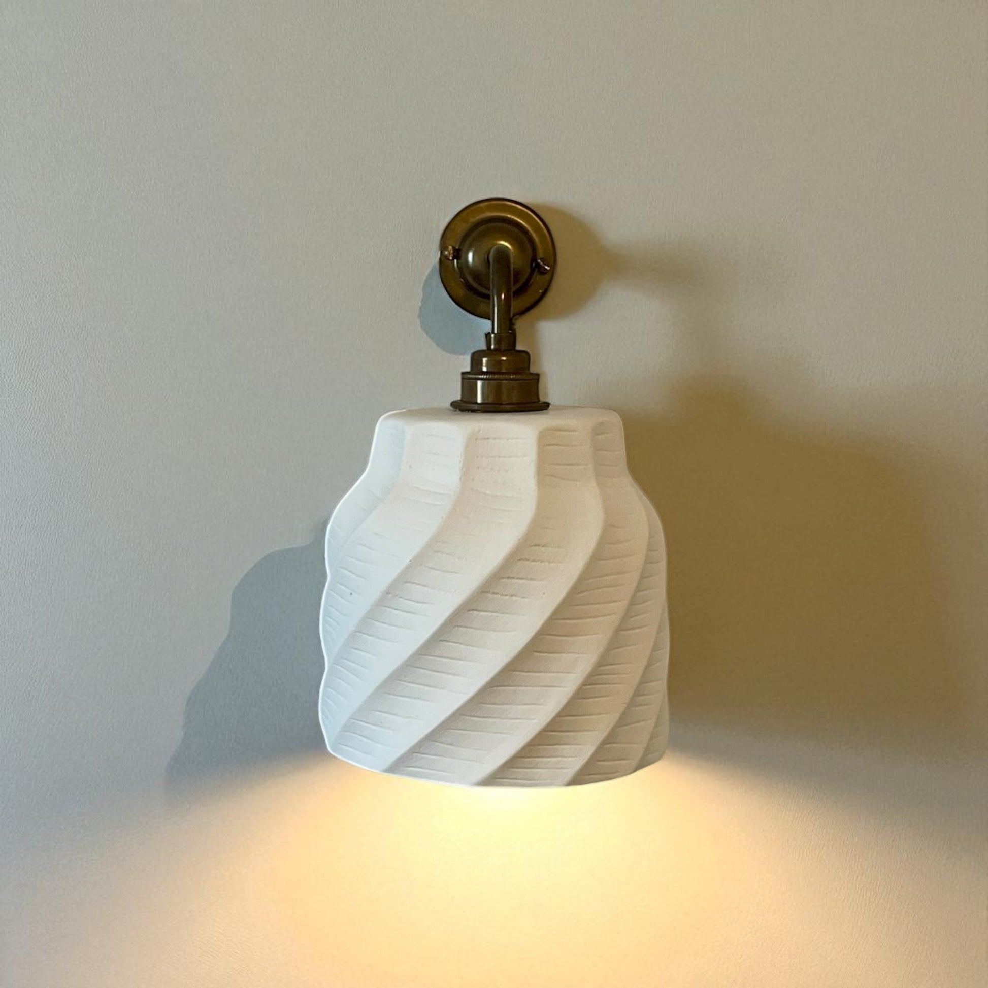wall sconce fixture with a textured white shade on a plain wall.