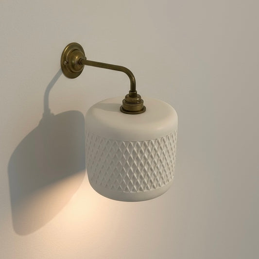 Wall-mounted lamp with white textured shade and brass arm on a plain wall.