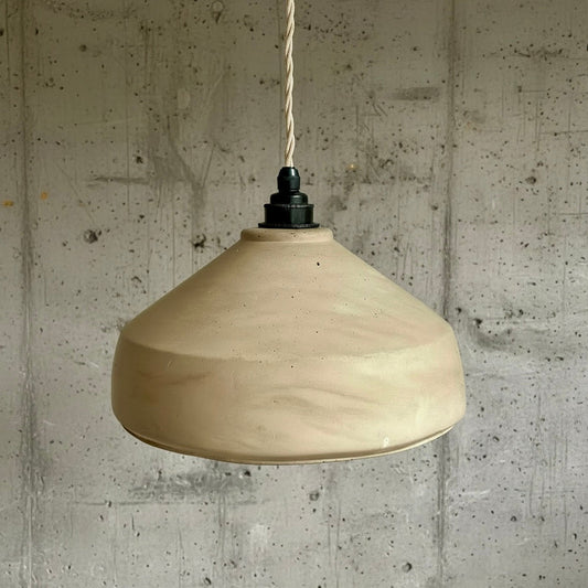 Beige pendant light hanging against a textured concrete wall