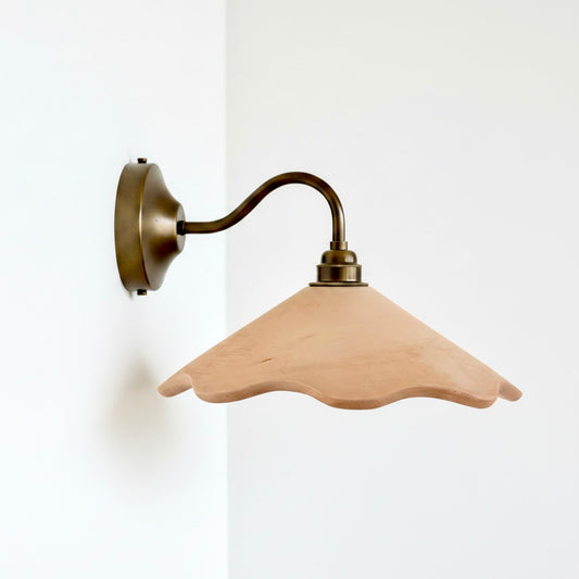 Wall-mounted light fixture with a beige glass shade on a white background