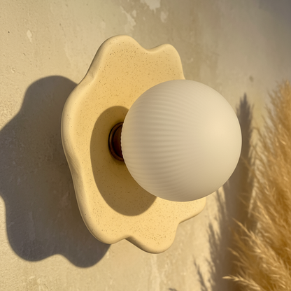 Decorative wall light fixture with a spherical bulb on a textured wall.