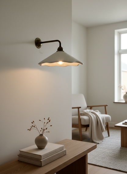 Wall-mounted lamp in a cozy living room setting with a vase and books on a table.
