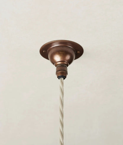 Bronze ceiling light fixture with white cord on a beige background