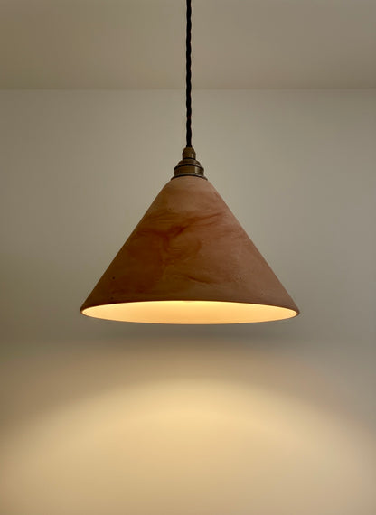 Conical pendant light with a warm glow on a neutral background