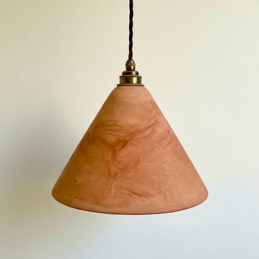 Terracotta cone-shaped pendant light against a plain background