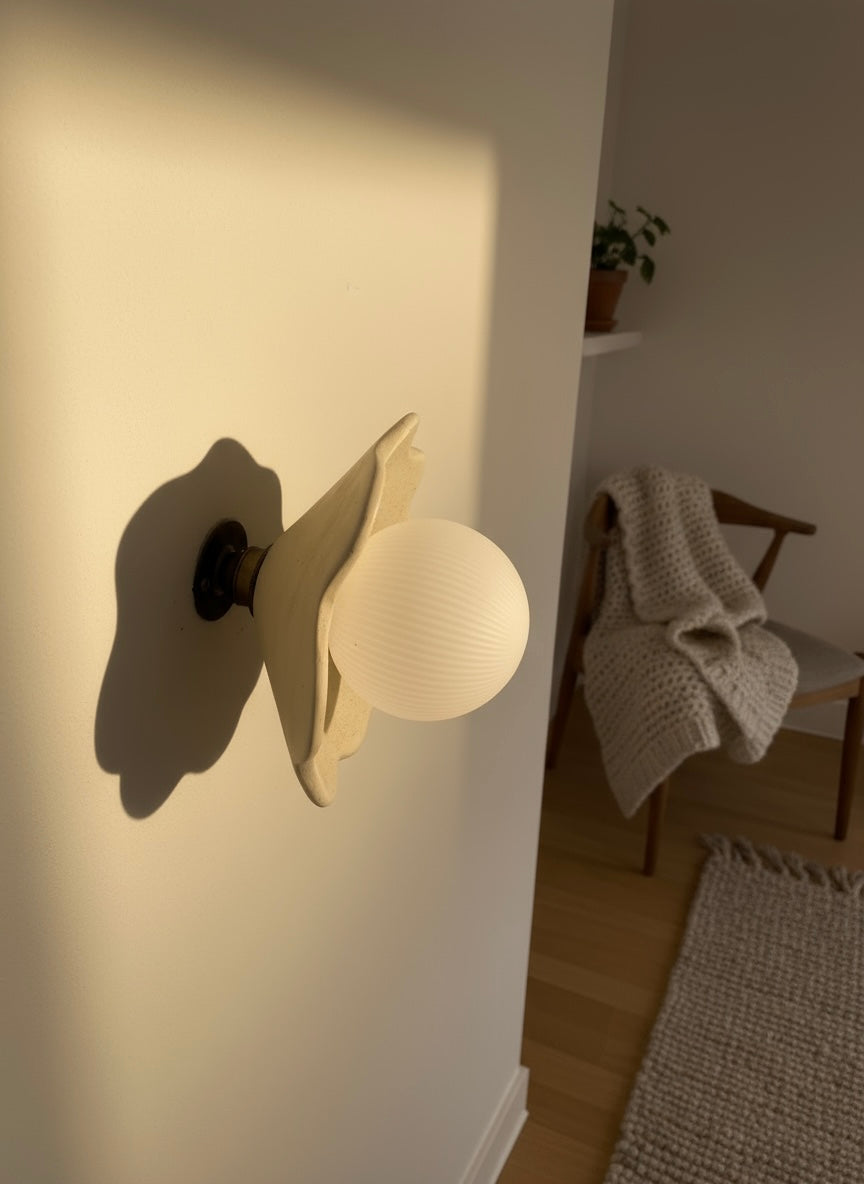 Wall-mounted lamp casting a shadow on a white wall with a cozy room setting.