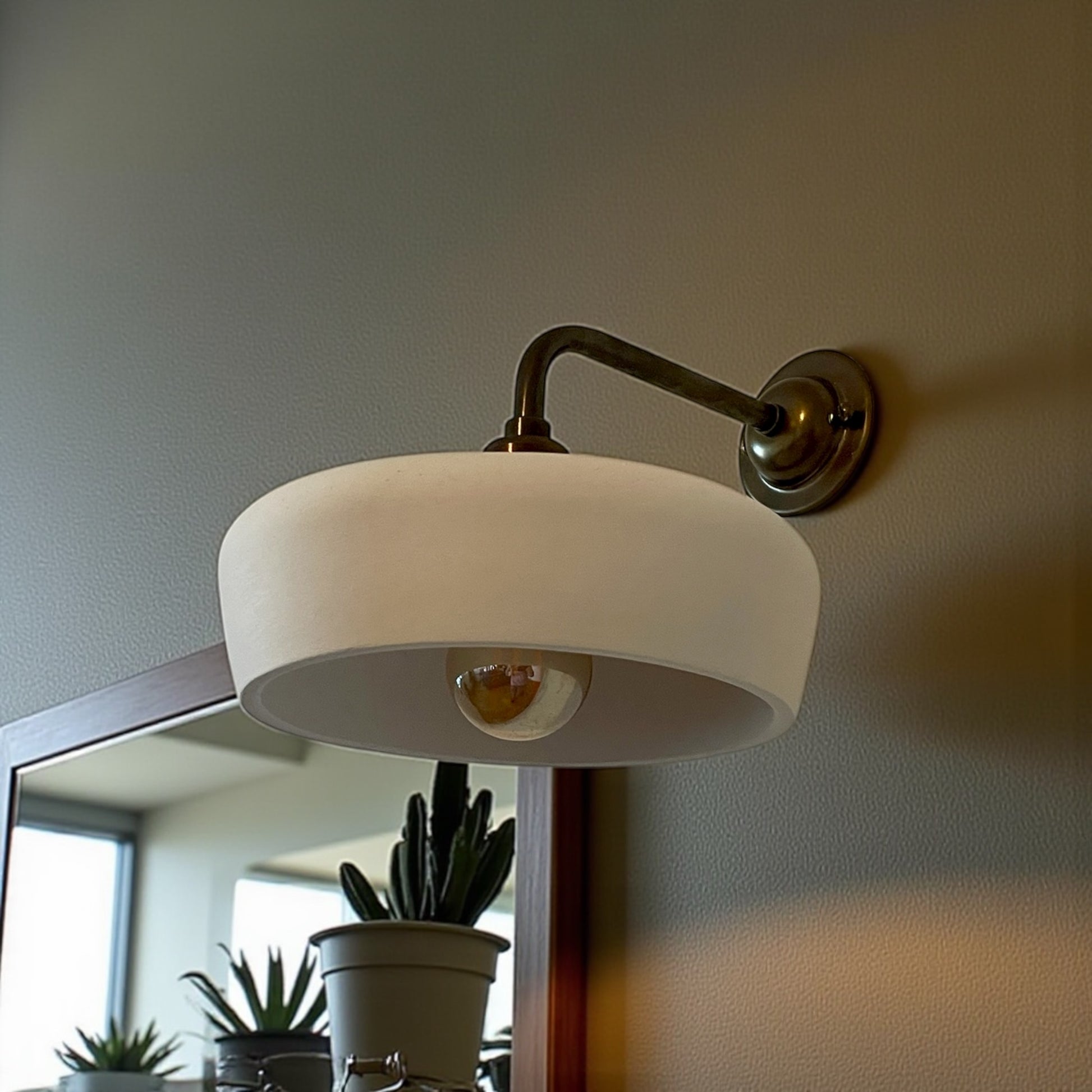 Wall-mounted lamp with a white shade on a neutral wall.