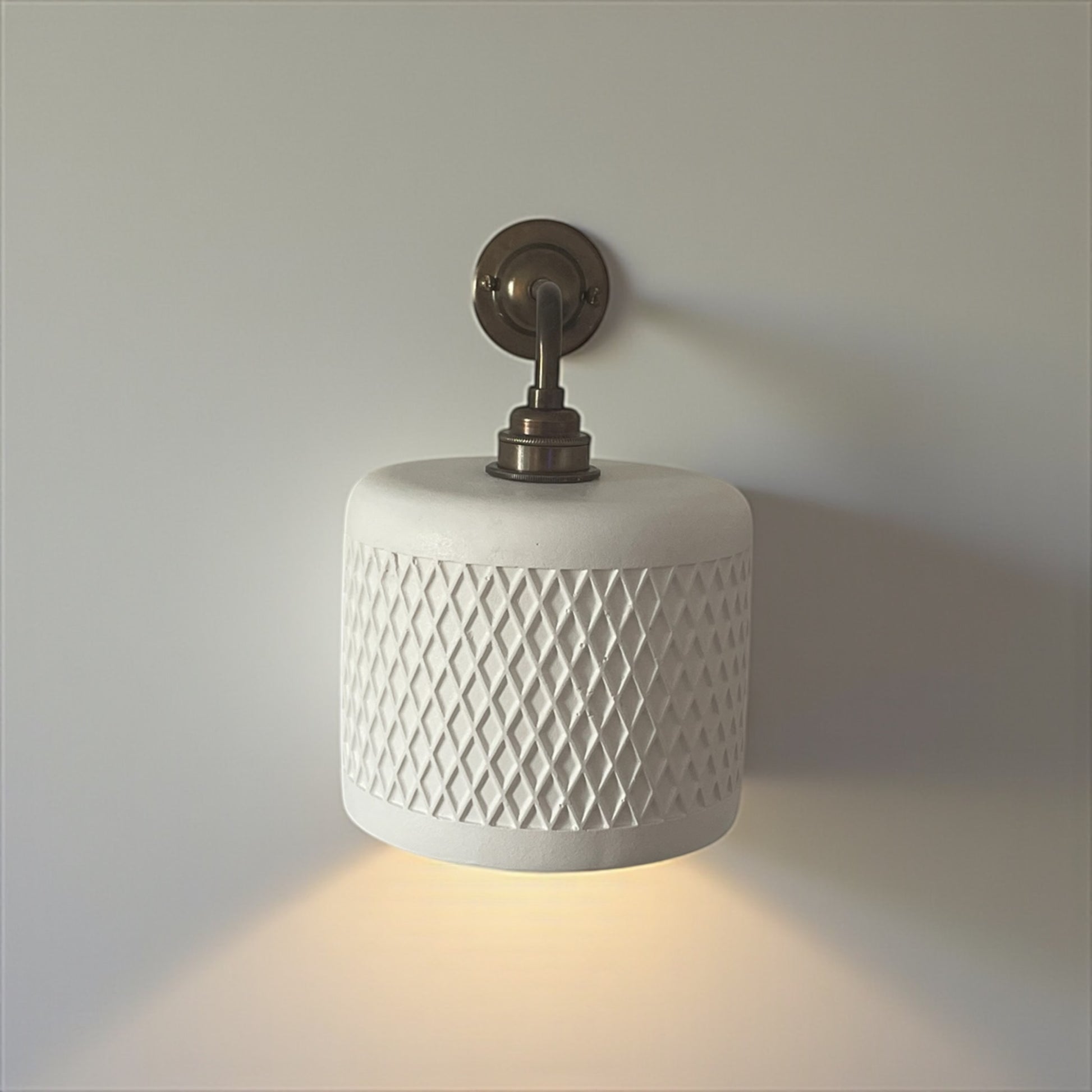 White wall sconce with decorative pattern on a neutral background