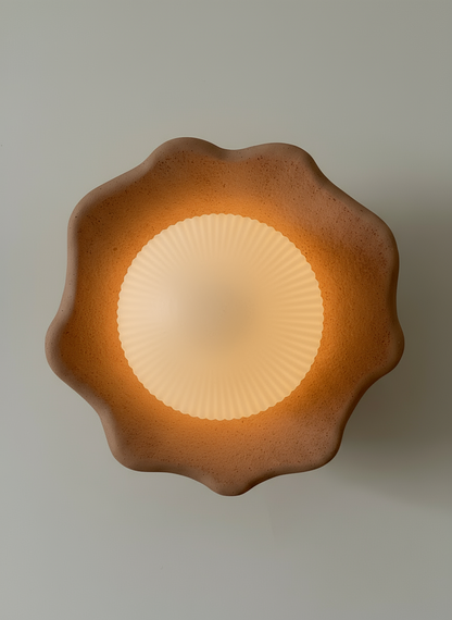 Decorative wall light fixture with a textured brown surface on a plain background