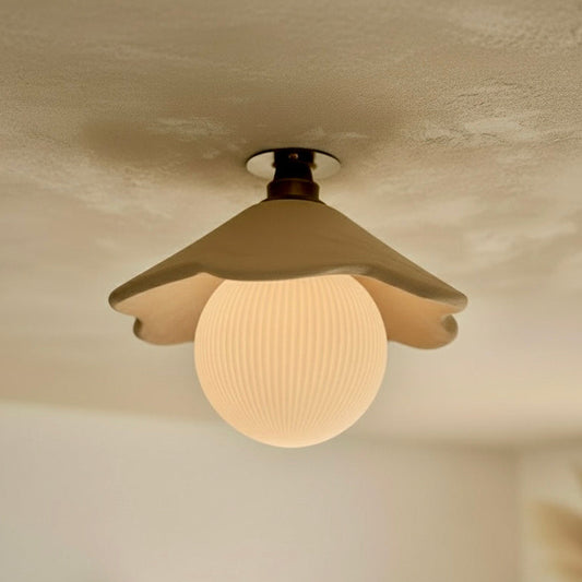 Ceiling light fixture with a glass shade on a textured ceiling.