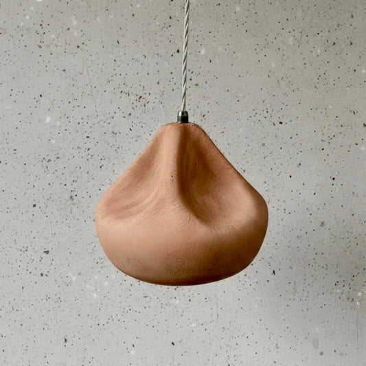 terracotta pendant light hanging against a gray concrete wall