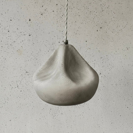Concrete pendant light hanging against a textured gray wall