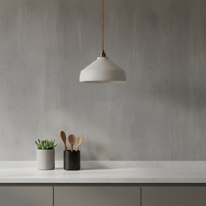 Modern kitchen setup with minimalist pendant light, plant, and utensils against a gray wall.