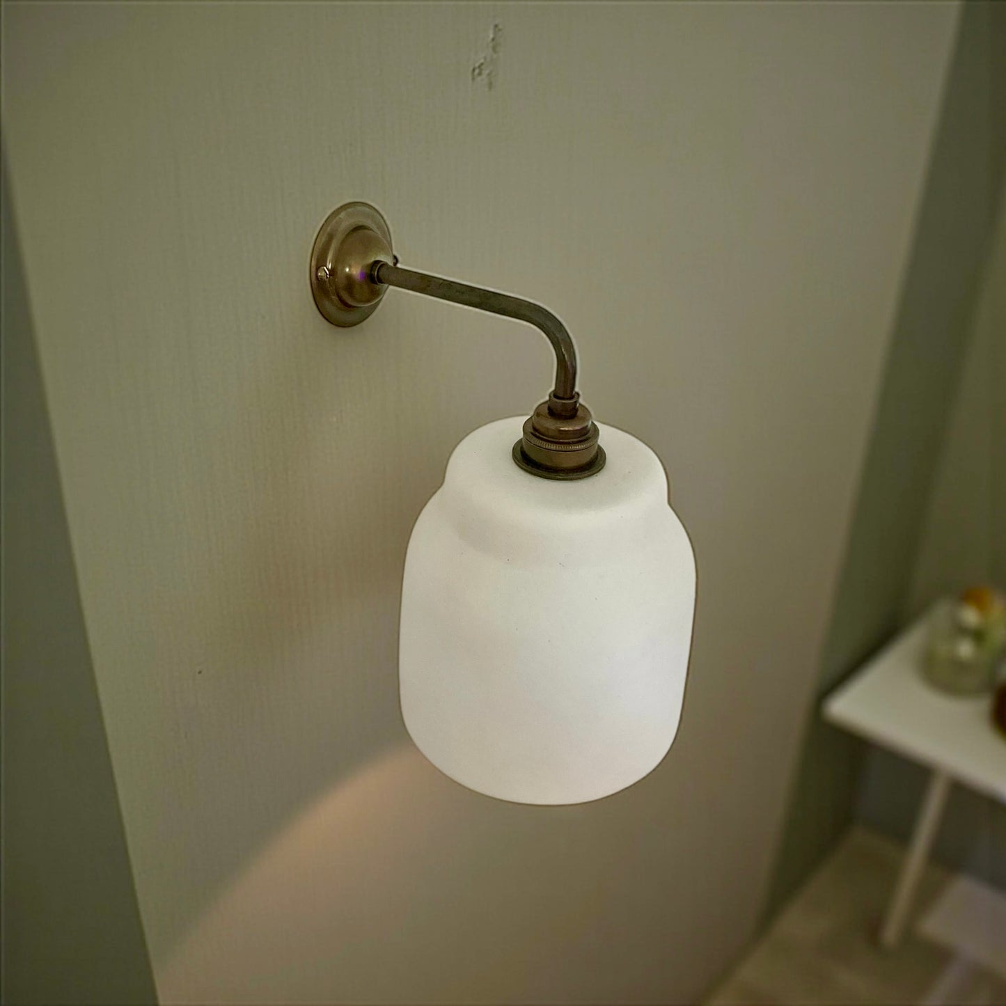 Handcrafted wall light fixture with white plaster shade on a plain wall.