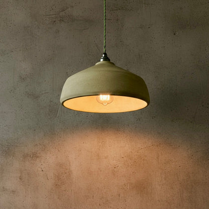 Green pendant light hanging against a textured wall