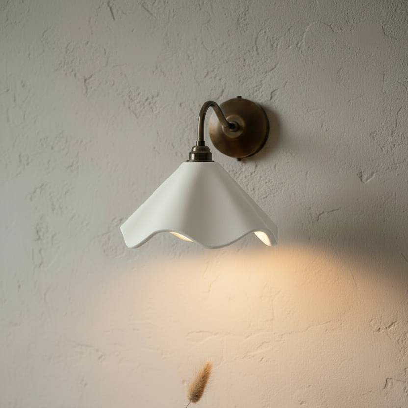 Wall-mounted lamp with a white shade and brass fixture on a textured wall.
