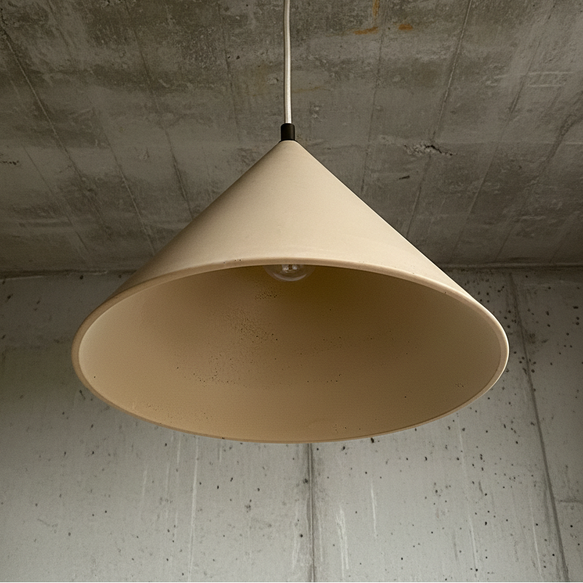 Beige pendant lamp hanging against a concrete wall.