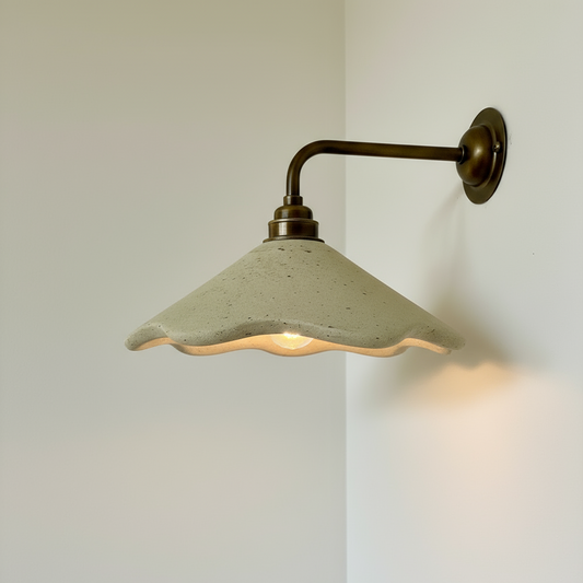 Wall sconce lamp fixture with green lampshade and brass arm on a white wall.