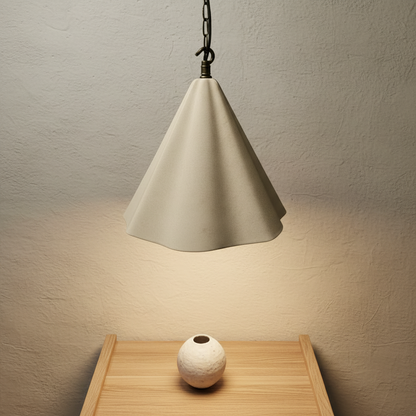 Beige cone-shaped pendant light casting a warm glow on a wooden surface with a small white vase.