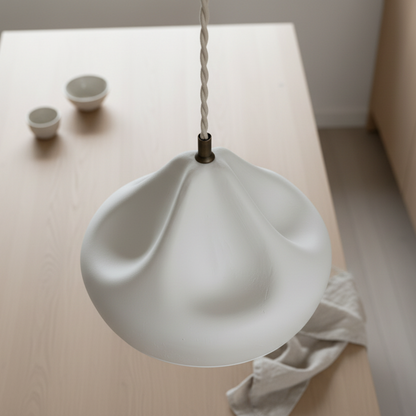 White plaster pendant light on a wooden surface with small bowls in the background