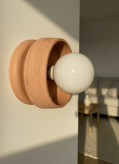 Wall-mounted light fixture with a wooden base and white bulb in a room setting.