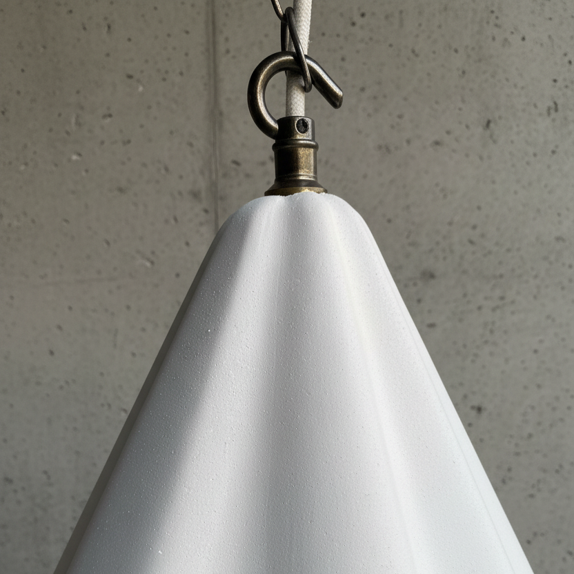 White cone-shaped lamp with a hook against a concrete wall