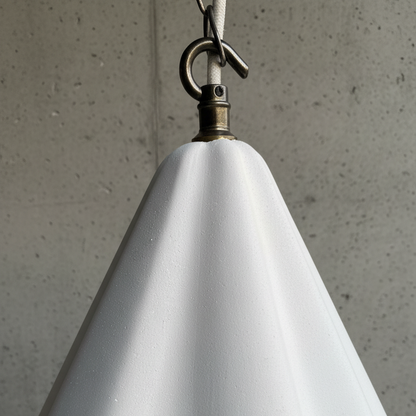 White cone-shaped lamp with a hook against a concrete wall