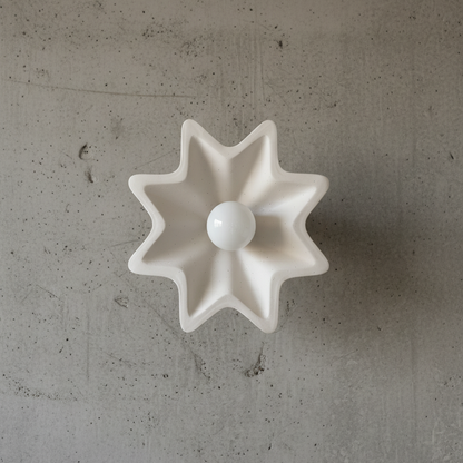 White star-shaped ceramic object on a gray concrete surface