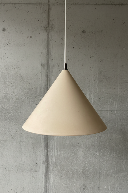 Beige cone-shaped pendant light against a concrete wall.