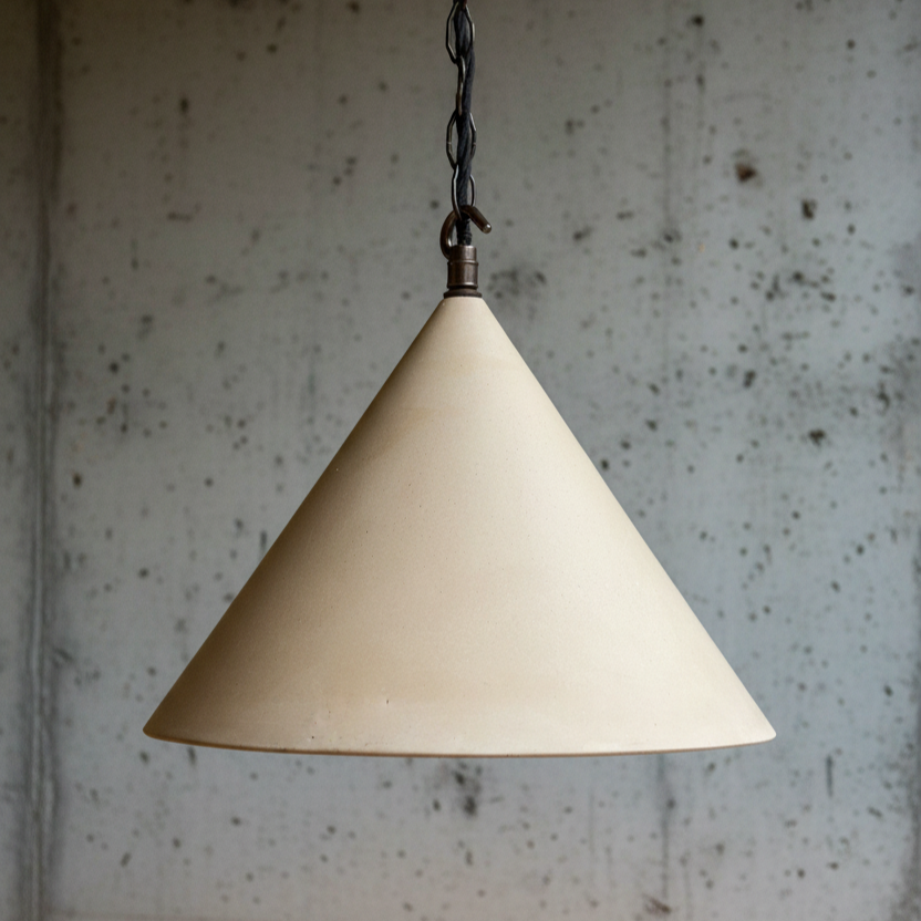 Beige cone-shaped pendant light against a textured wall.