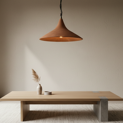 Wooden table with a vase and decorative items under a brown pendant light against a beige wall.
