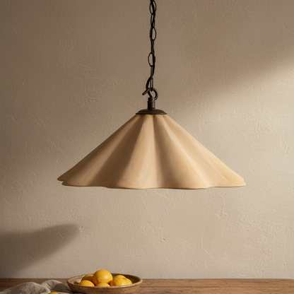 Beige pendant light hanging against a beige wall with a bowl of lemons on a wooden surface.