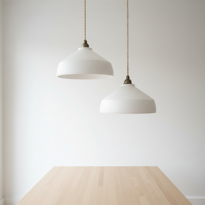 Two white pendant lights hanging above a wooden table with a plain white background