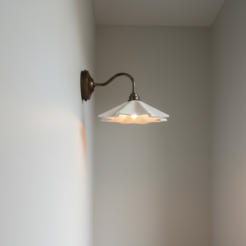 Wall-mounted lamp with a white shade on a plain wall, next to a wooden table with a ceramic bowl.