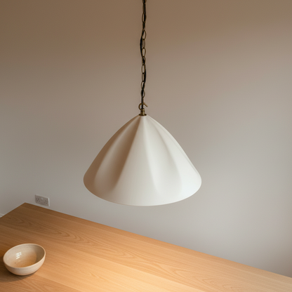 White pendant light hanging above a wooden table with a neutral wall background