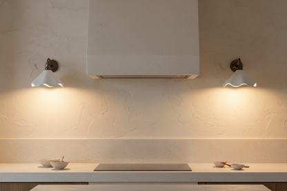 Modern kitchen with white cabinets, countertop, and wall lights.