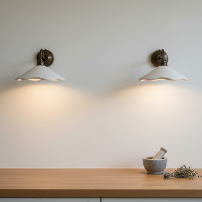 Two wall-mounted lights on a white wall with a wooden surface and a mortar and pestle in the foreground.