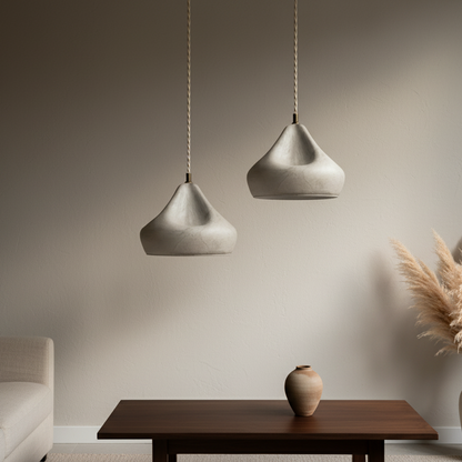 Two pendant lights hanging above a wooden table with decorative elements in a room.