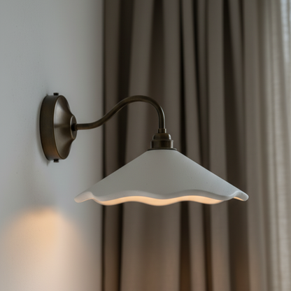 White scalloped wall light with a white glass shade against a neutral background