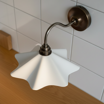 Wall-mounted lamp with white shade and bronze fixture against a tiled wall.