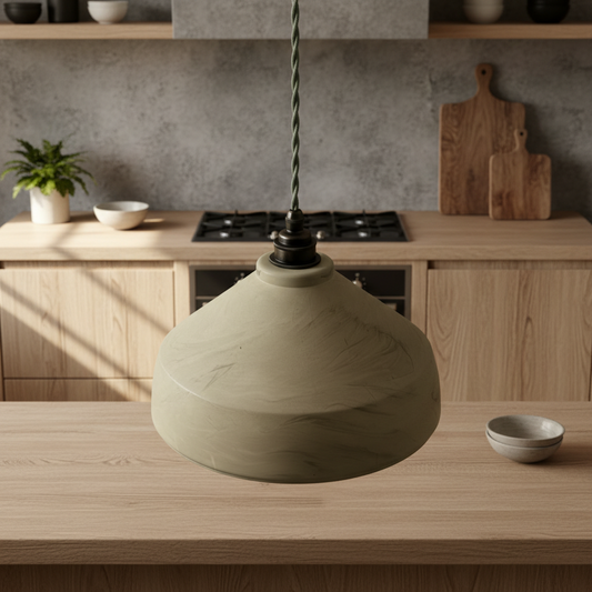 Sage green pendant light on a wooden table with a kitchen in the background