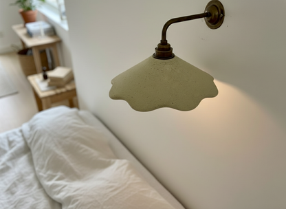 Wall-mounted light fixture on a white wall with a blurred room background
