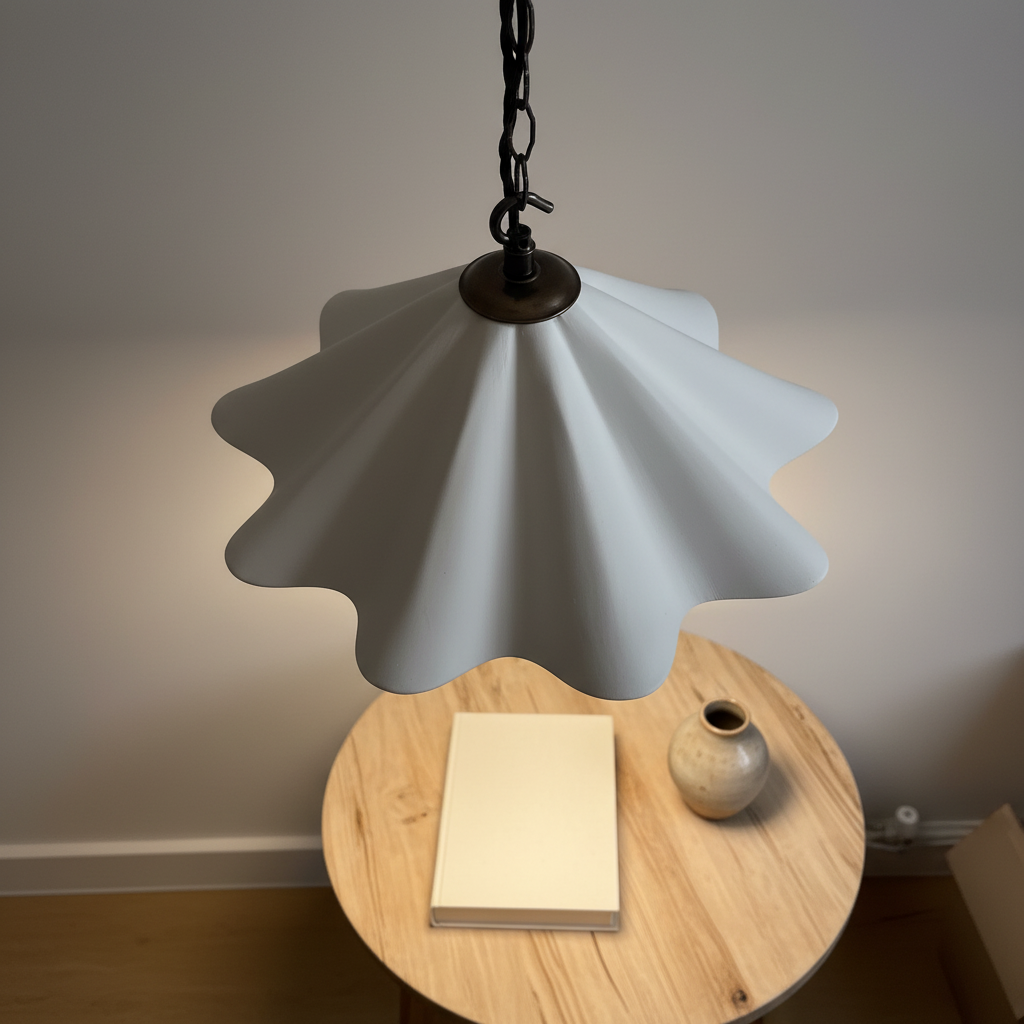 Pendant light with scalloped design on a wooden table against a neutral wall.