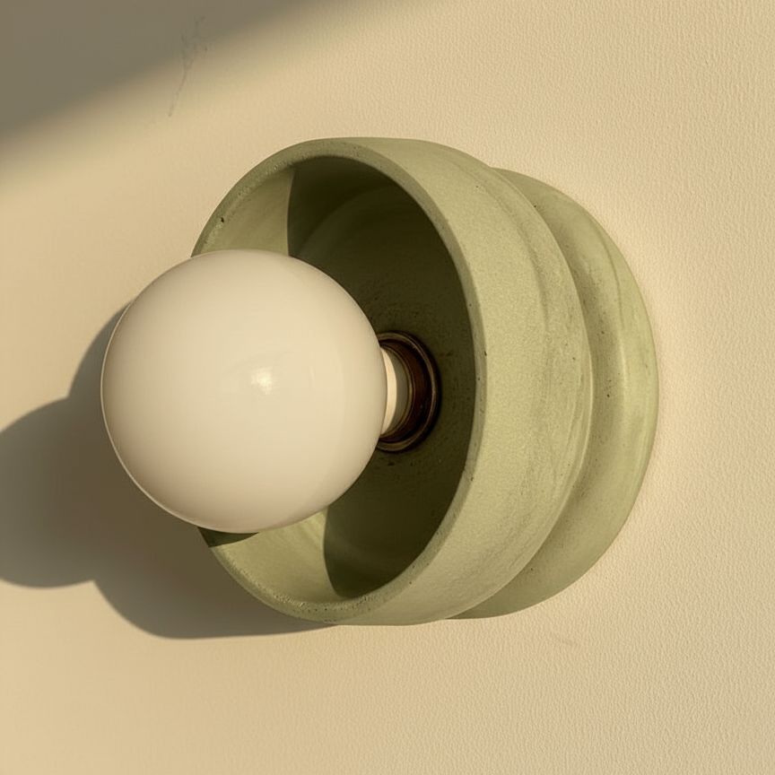 Pale green plaster wall lamp against a beige background