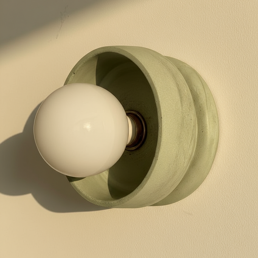 Pale green plaster wall lamp against a beige background