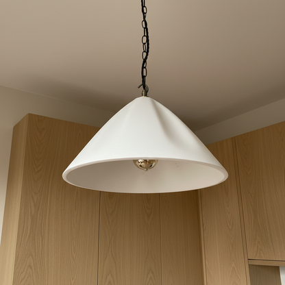 White pendant light hanging above wooden kitchen cabinets.