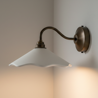 White wavy sconce with white shade and bronze arm on a neutral wall.